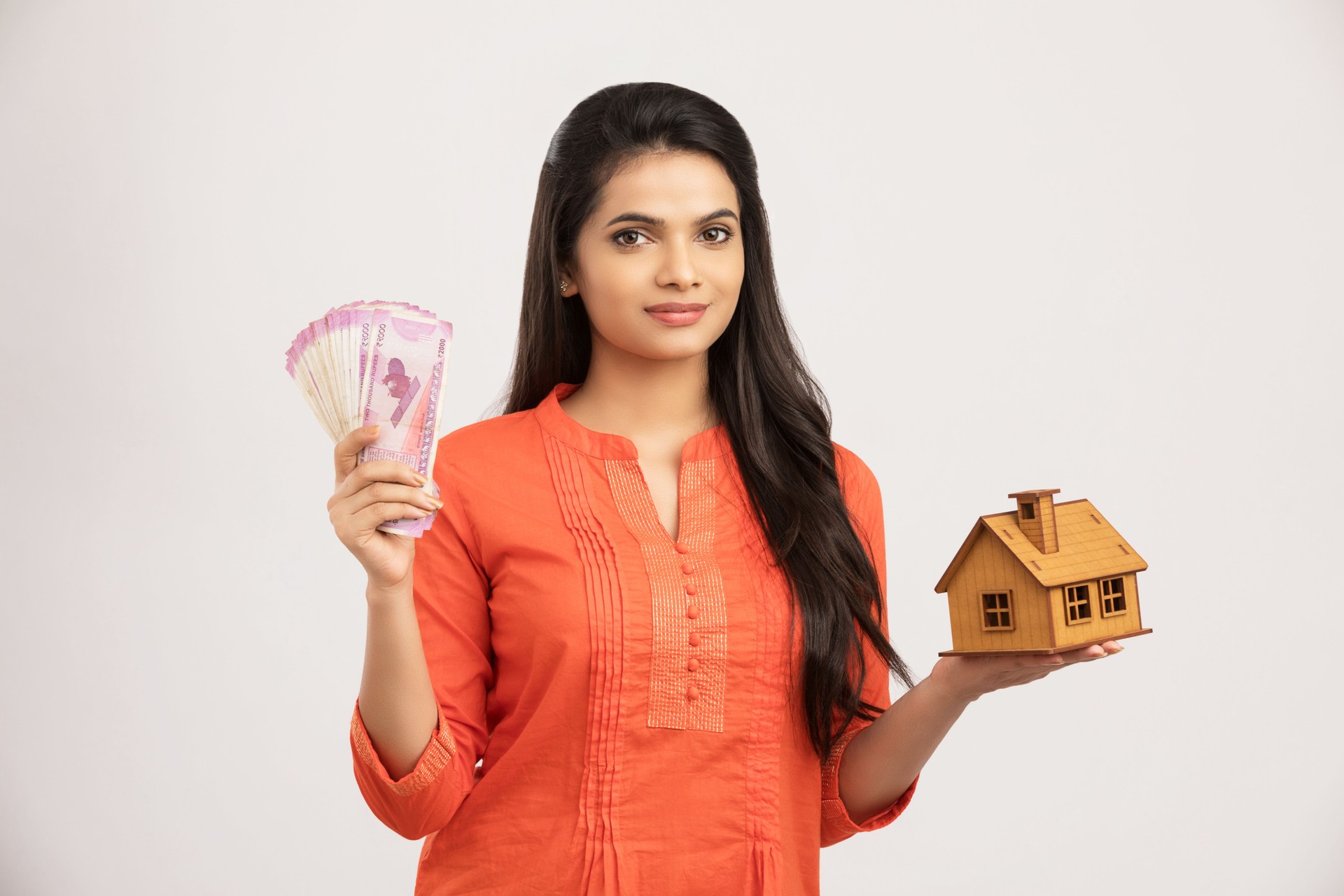 Cute Indian woman holding an house model and Indian money