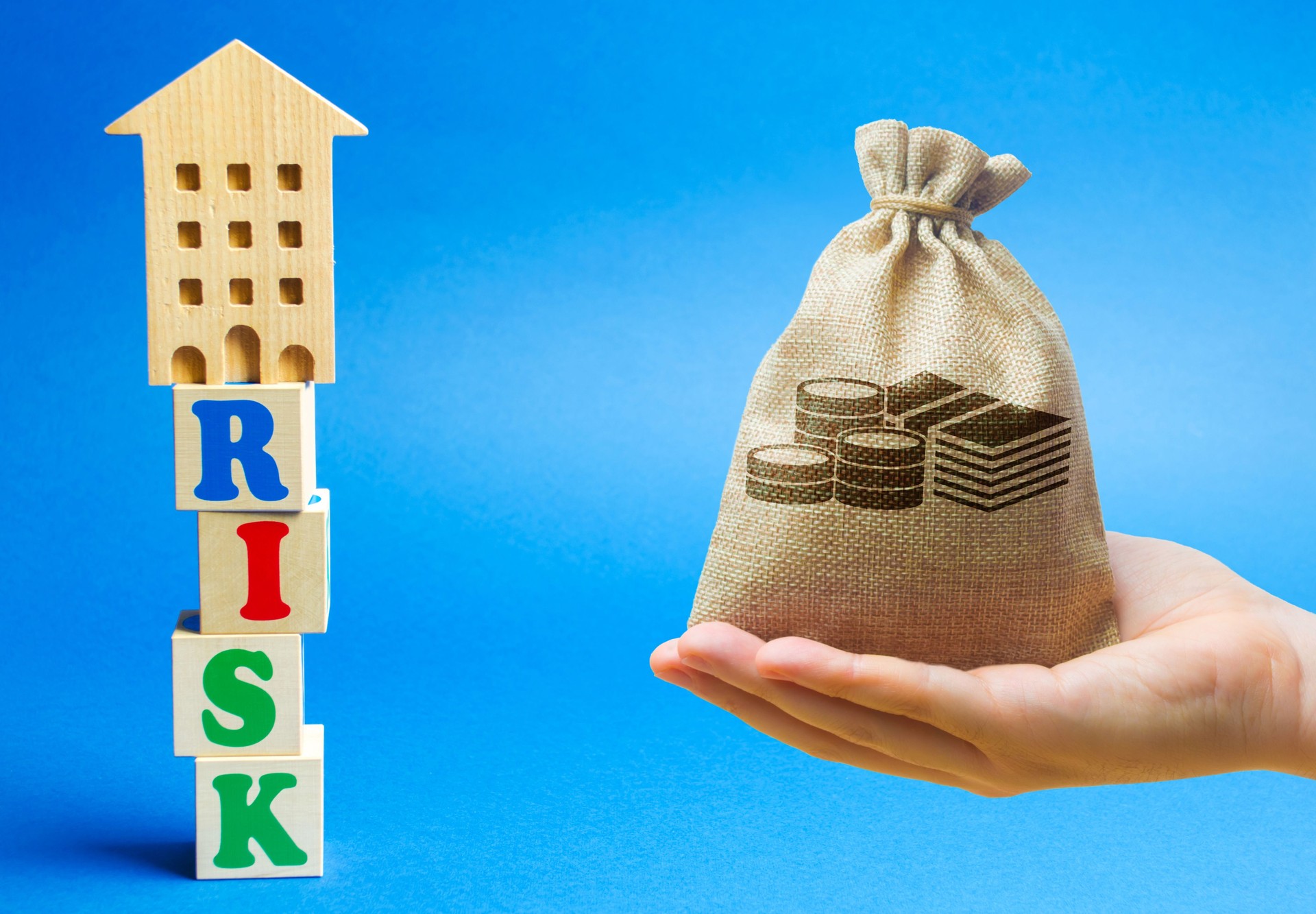 Wooden blocks with the word Risk and a miniature house with money bag. Real estate investment risks. Risky investments. Loss of property for non-payment. Debts. Mortgage tax.