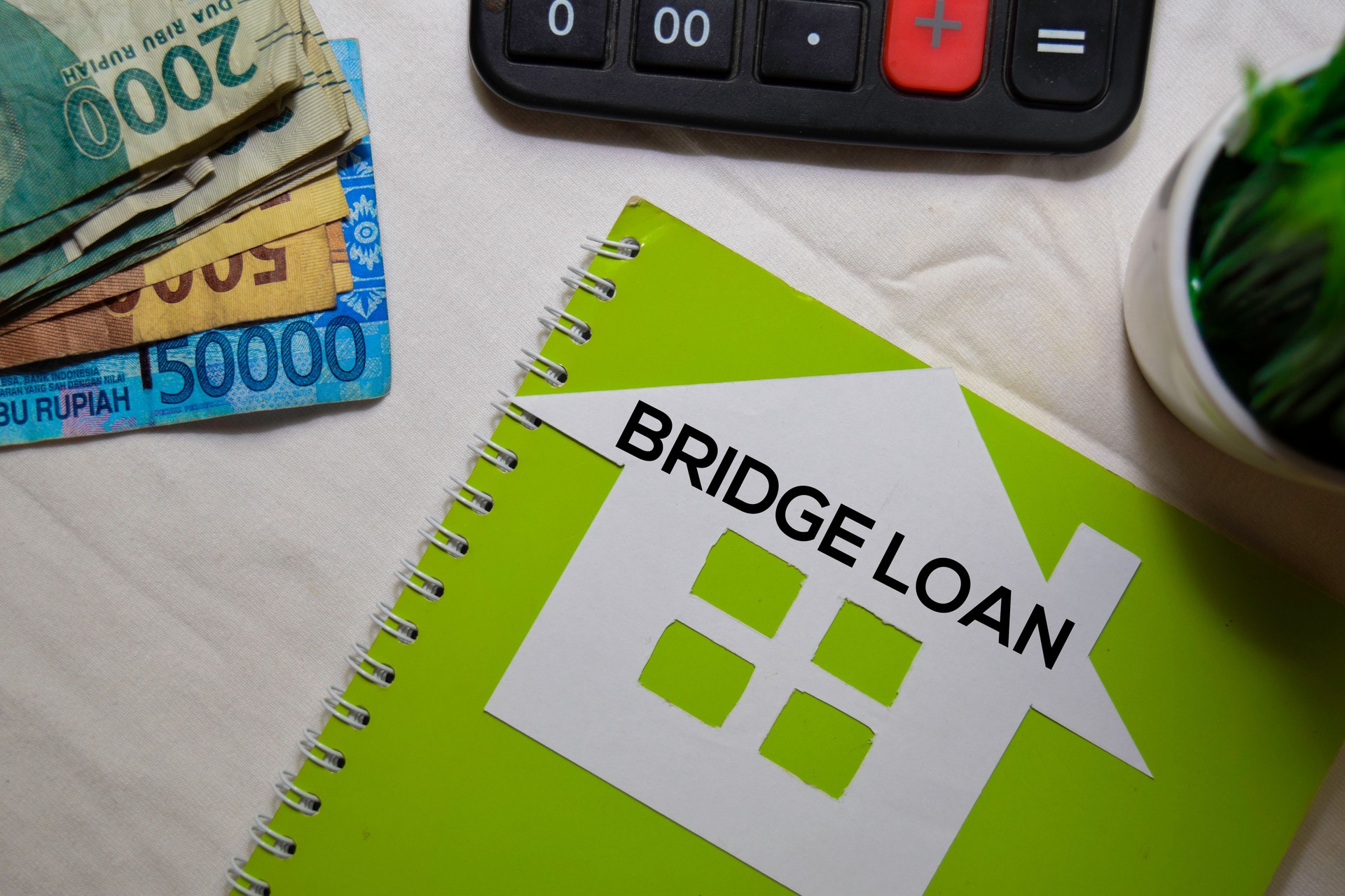Bridge Loan text on paper house and Indonesian Rupiah isolated on office desk.