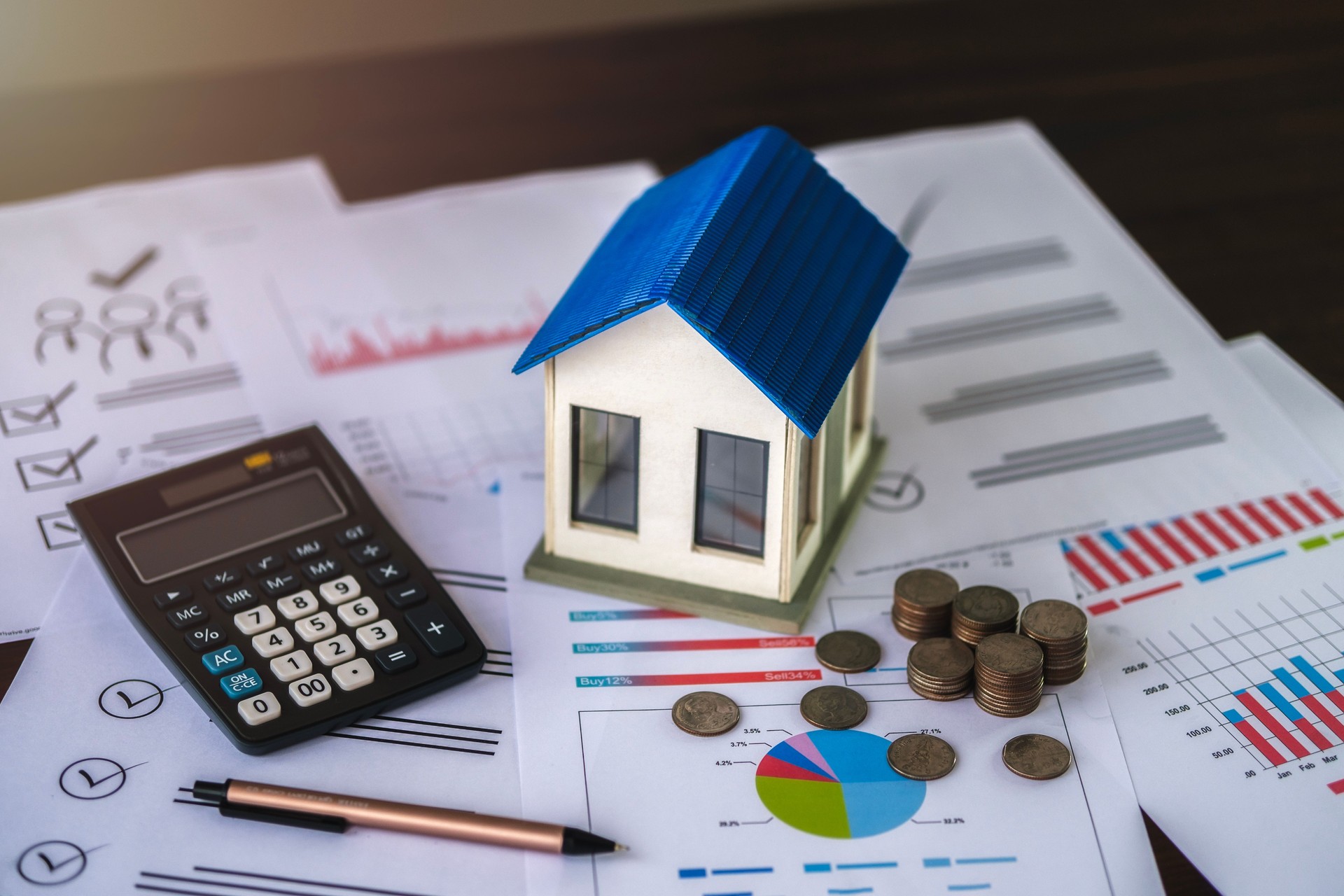 View of house model and pile of coins placed on document. Concept. Real estate business. Investment planning and property taxes Bank concept, loan, home sale and home insurance concept.